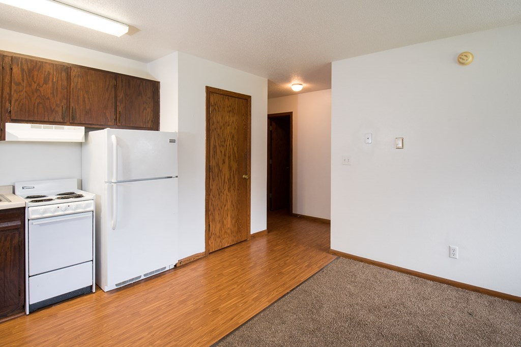 A kitchen with white appliances and wooden cabinets.