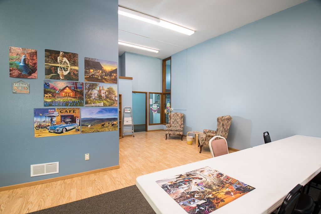 A room with a white table and chairs, a blue wall, and pictures on the wall.