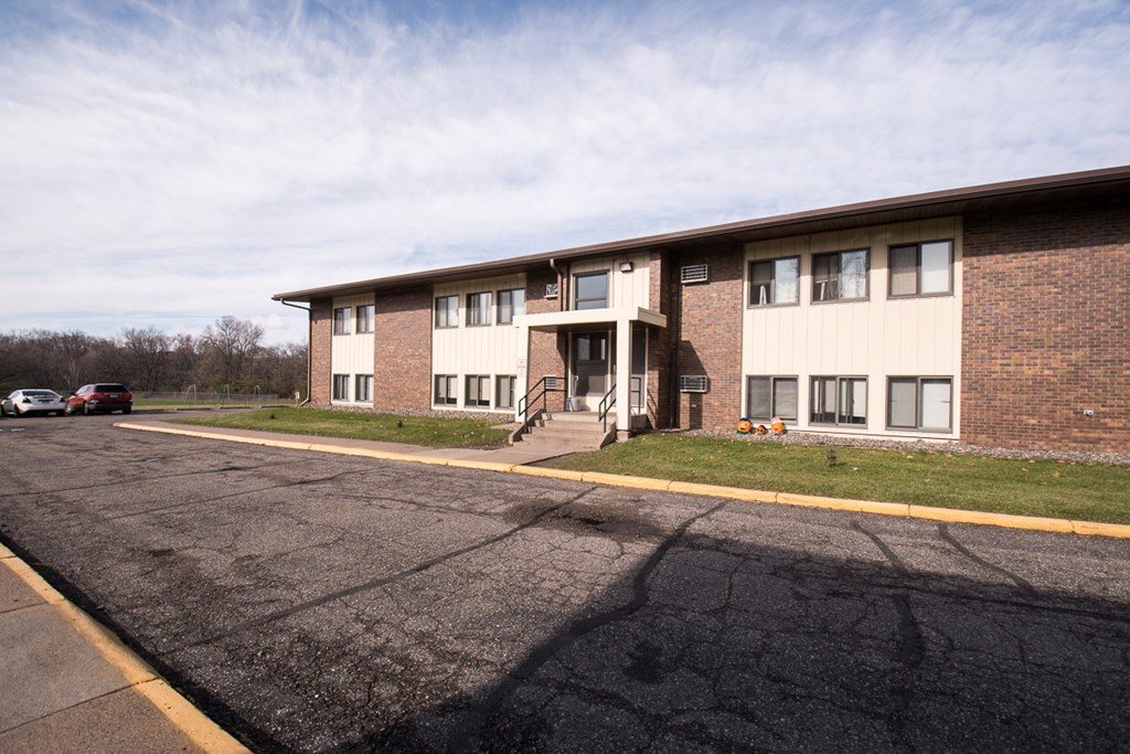 A parking lot in front of a brick building with a yellow line.
