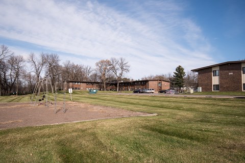 A playground with a swing set and a building in the background.
