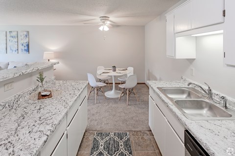 A kitchen with a marble countertop and white cabinets.