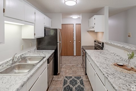 A kitchen with granite countertops and white cabinets.
