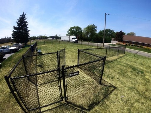 A large black fenced area in the middle of a grassy field.