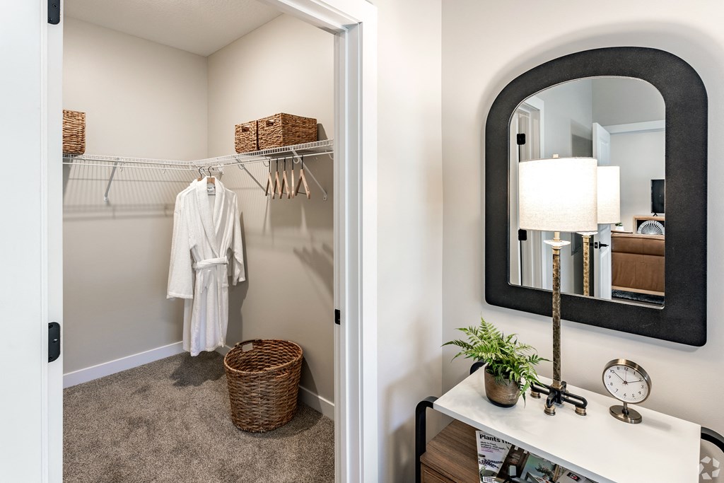 a hallway with a mirror and a closet with a white robe and a dresser