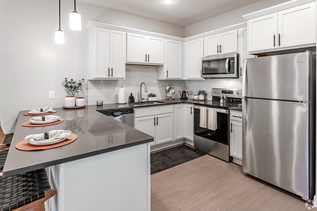 an open kitchen with stainless steel appliances and white cabinets