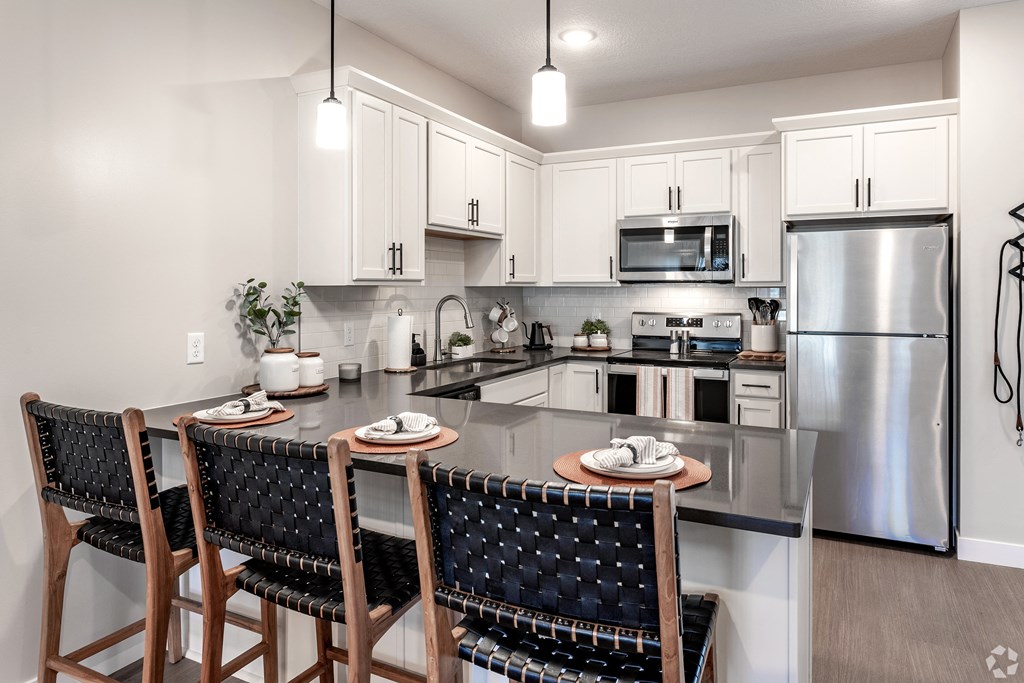 spacious kitchen with stainless steel appliances and a island with chairs