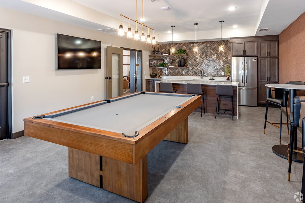 a pool table in a clubhouse with a kitchen and a bar