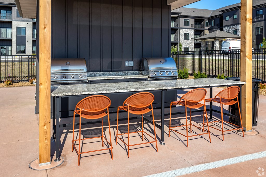 a bar with chairs in front of a grill