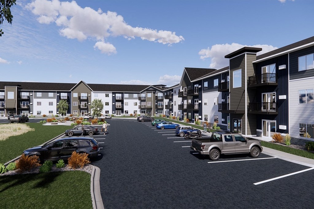 A row of modern townhouses with cars parked in front.