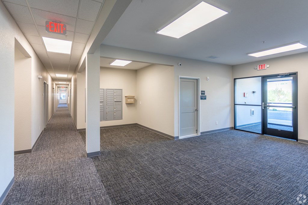 A long hallway with exit signs on the wall.
