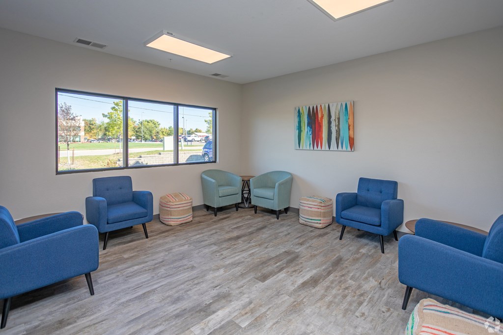 A room with blue chairs and a painting on the wall.
