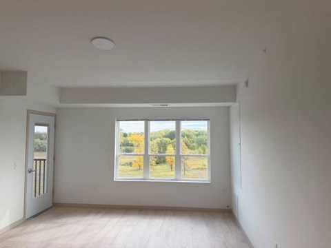 A room with a large window overlooking a field.