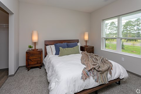 A bedroom with a large bed and two lamps.