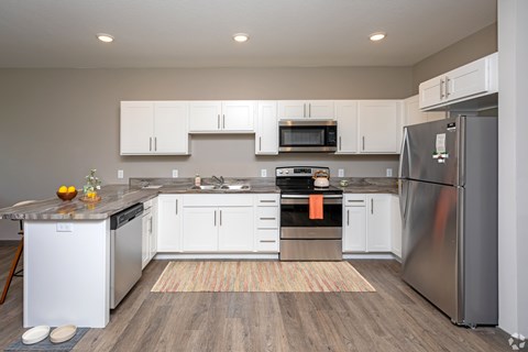 A modern kitchen with white cabinets and stainless steel appliances.