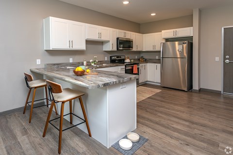 A kitchen with a marble island and stainless steel appliances.