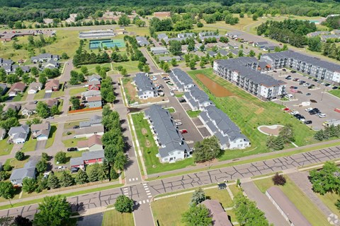 A bird's eye view of a residential area with apartment buildings, houses, and a swimming pool.