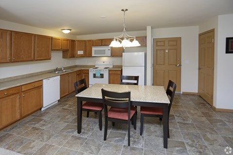 A kitchen with a table and chairs in the middle.