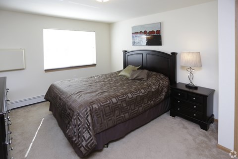 A bedroom with a large bed and a nightstand with a lamp.