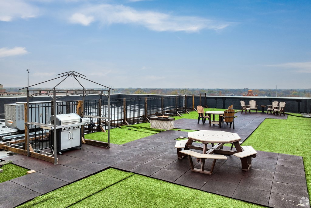 a rooftop patio with tables and chairs and a grill