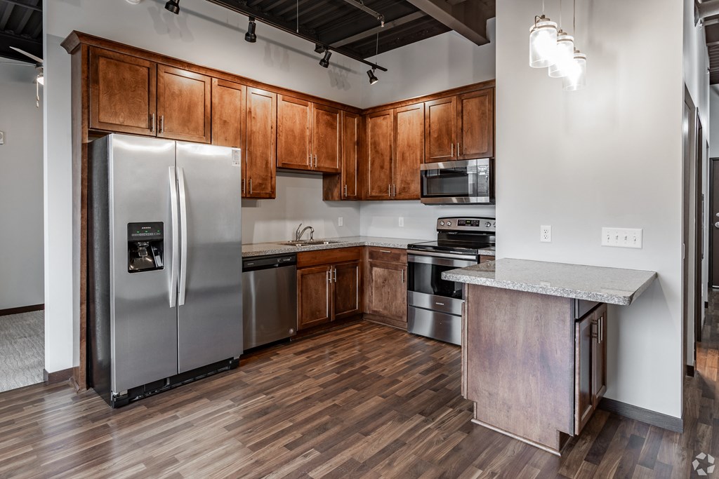 an empty kitchen with stainless steel appliances and wooden cabinets
