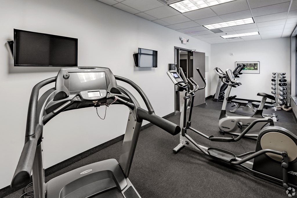 a gym with various exercise machines and a tv