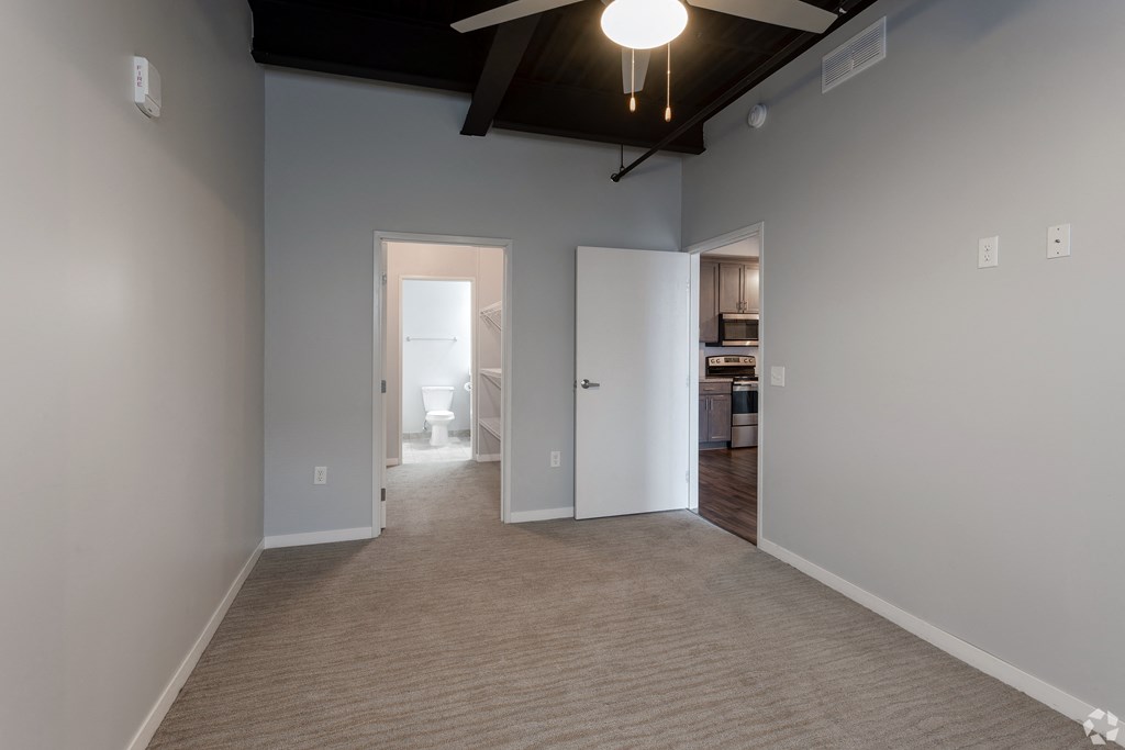 an empty living room with a carpet and a ceiling fan