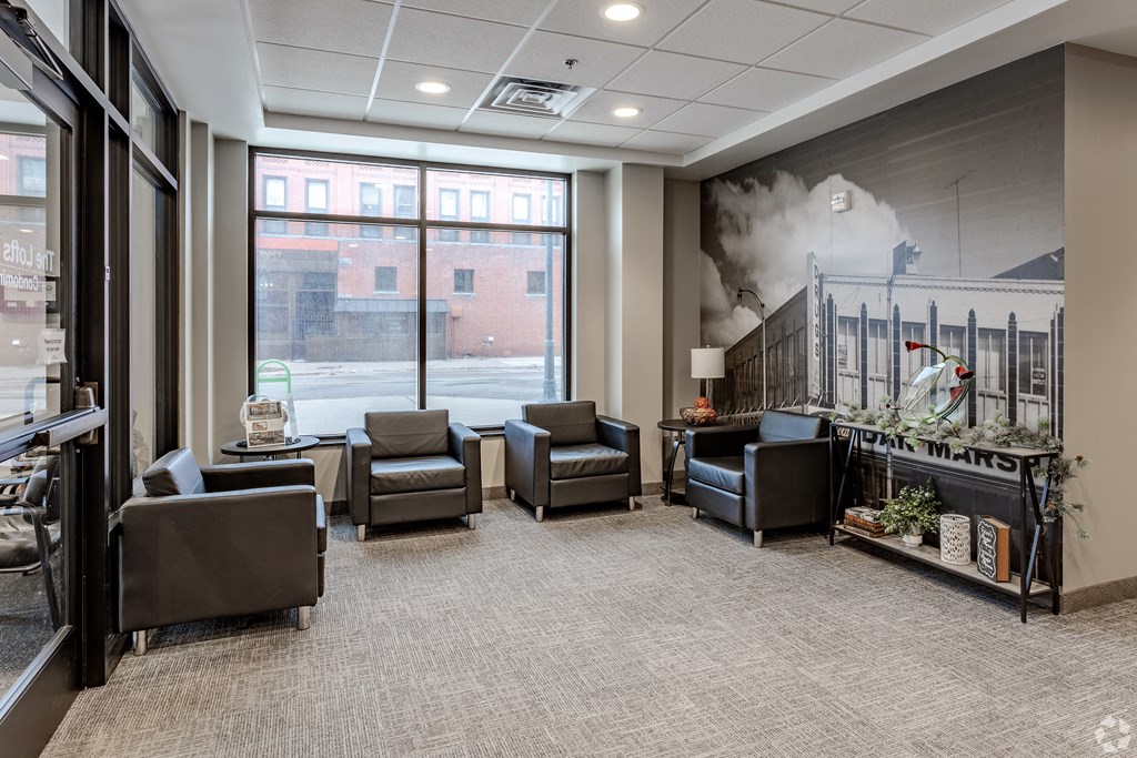 a lobby with chairs and a fireplace and a large window