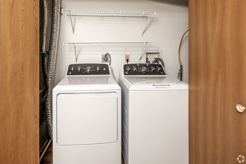 Two white front loading washing machines in a laundry room.