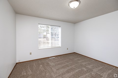A room with a carpeted floor and a window.