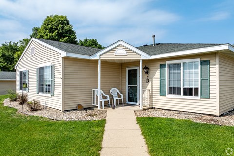 A beige house with a white door and a small porch.