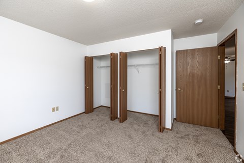 A room with a carpeted floor and three open doors.