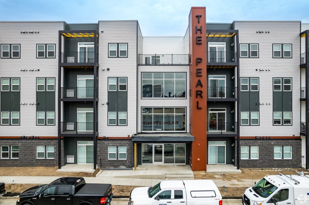 The Pearl apartment building with cars parked in front.