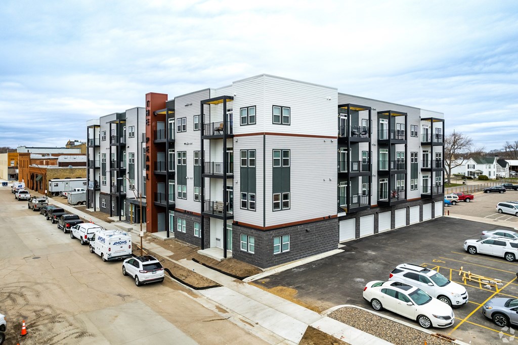 A parking lot with cars and a building with many windows.