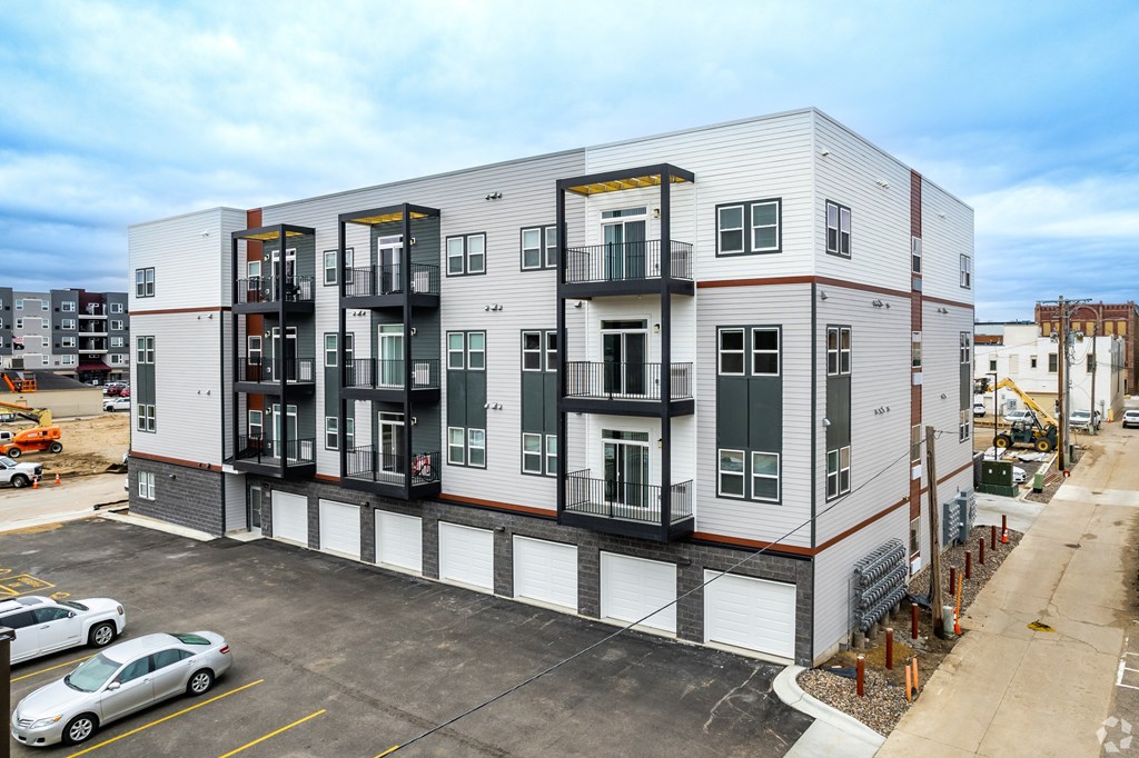 A modern apartment building with a parking lot in front.