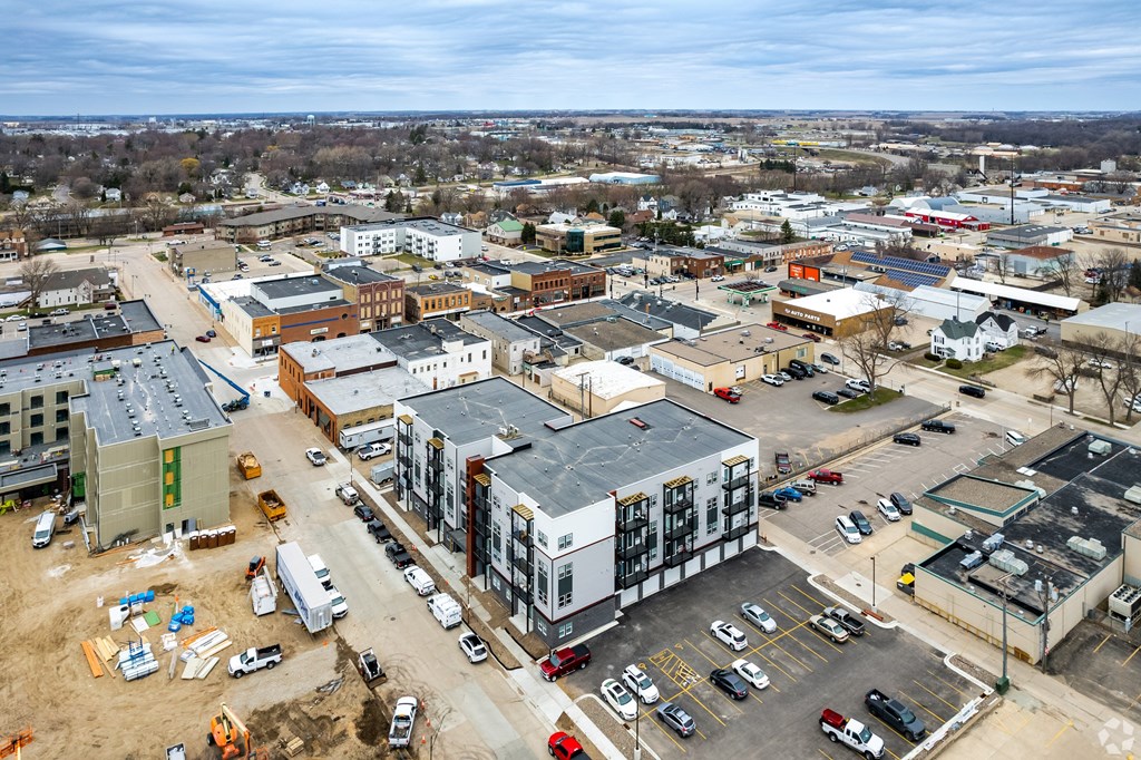 A construction site is visible in the foreground of a busy parking lot.