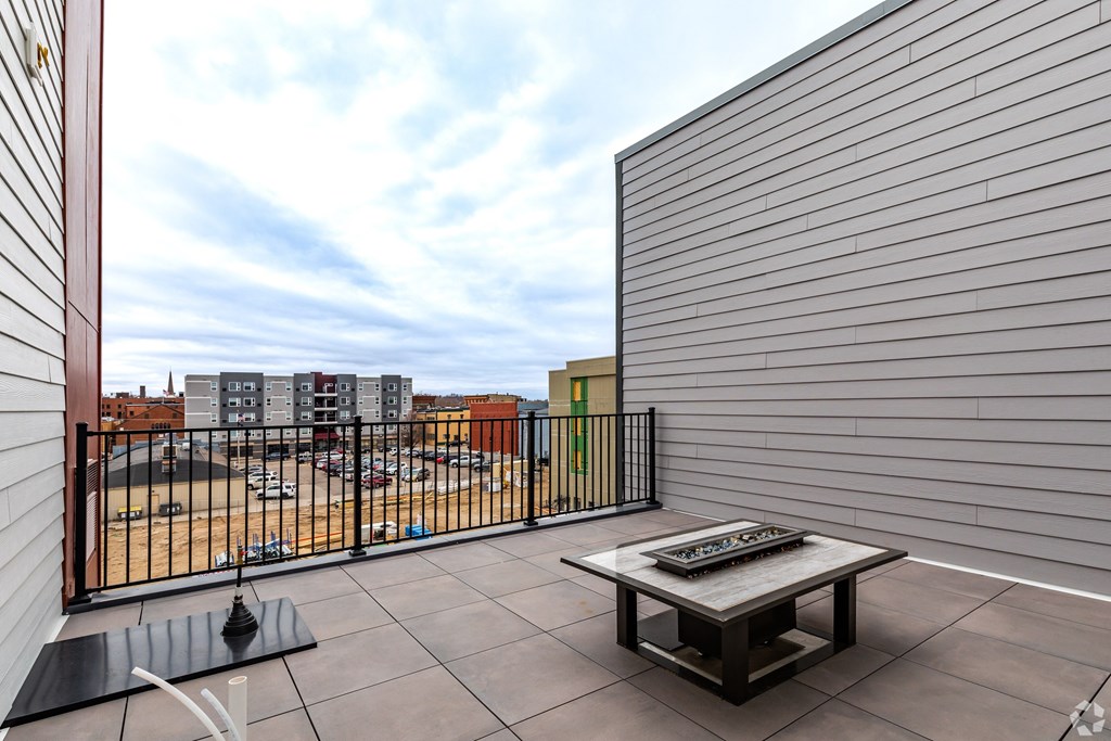 A balcony with a table and chairs overlooking a parking lot.