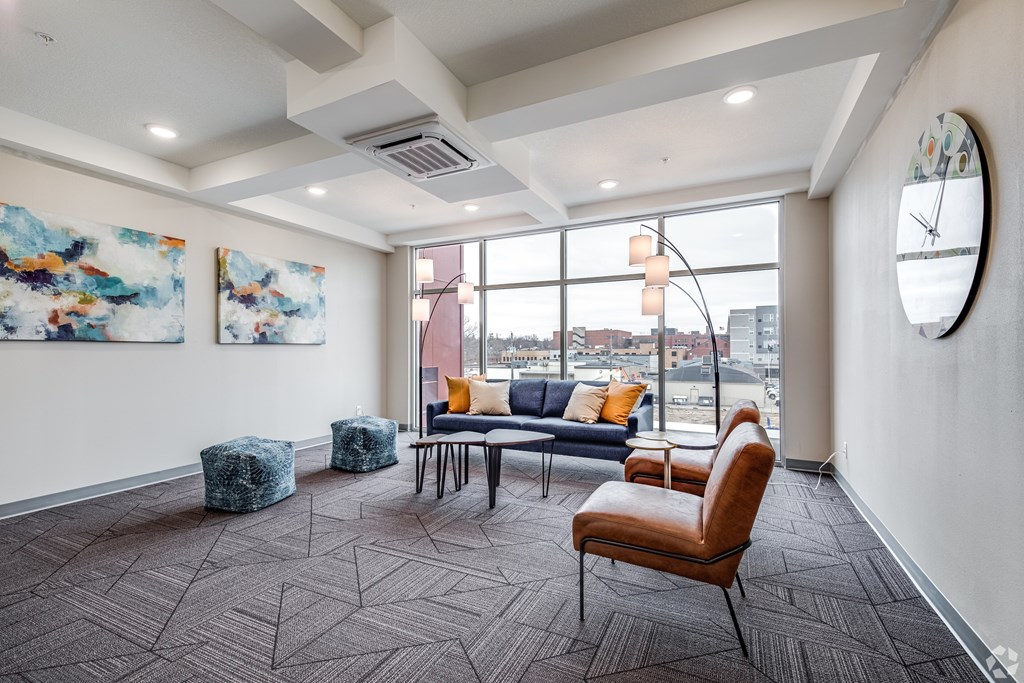 A room with a chair, a table, and two paintings on the wall.