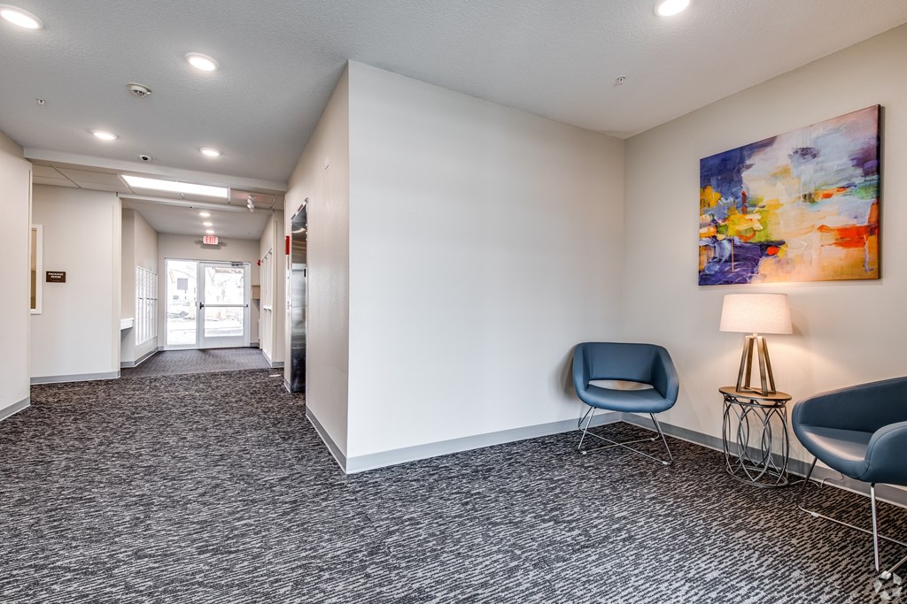 A hallway with a blue chair and a painting on the wall.