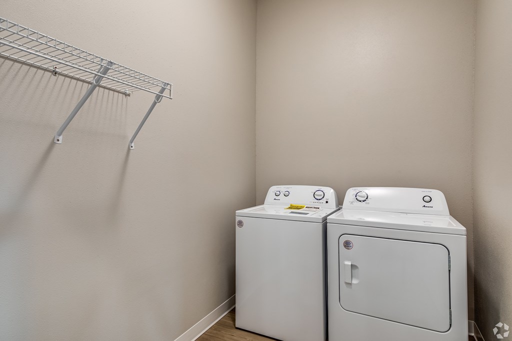 Two white front loading washing machines in a laundry room.