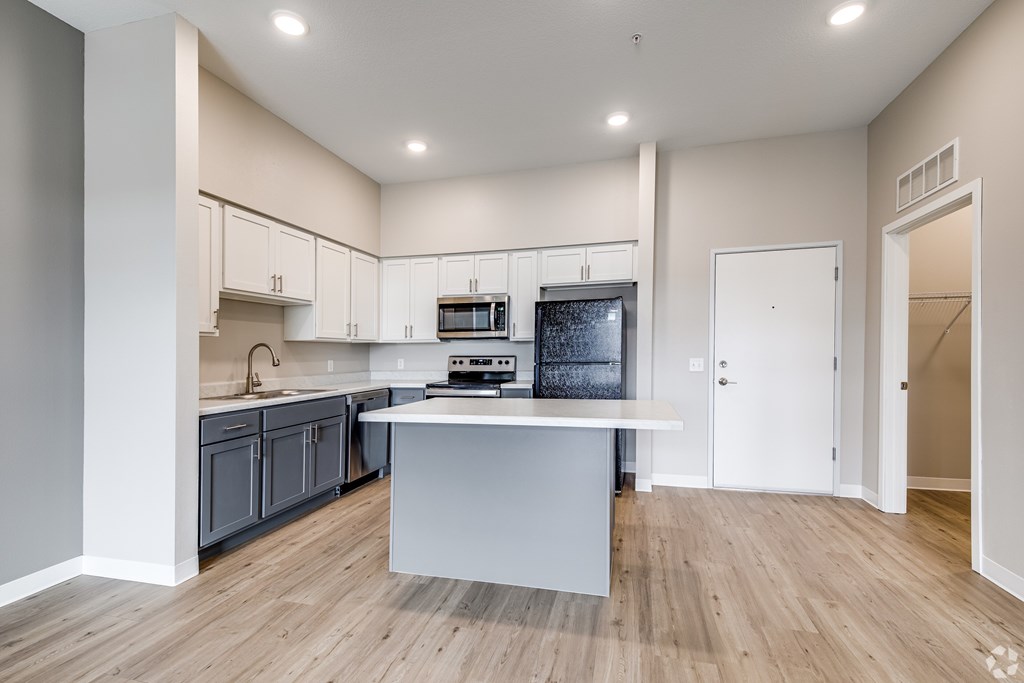 A kitchen with a white island and wooden floors.