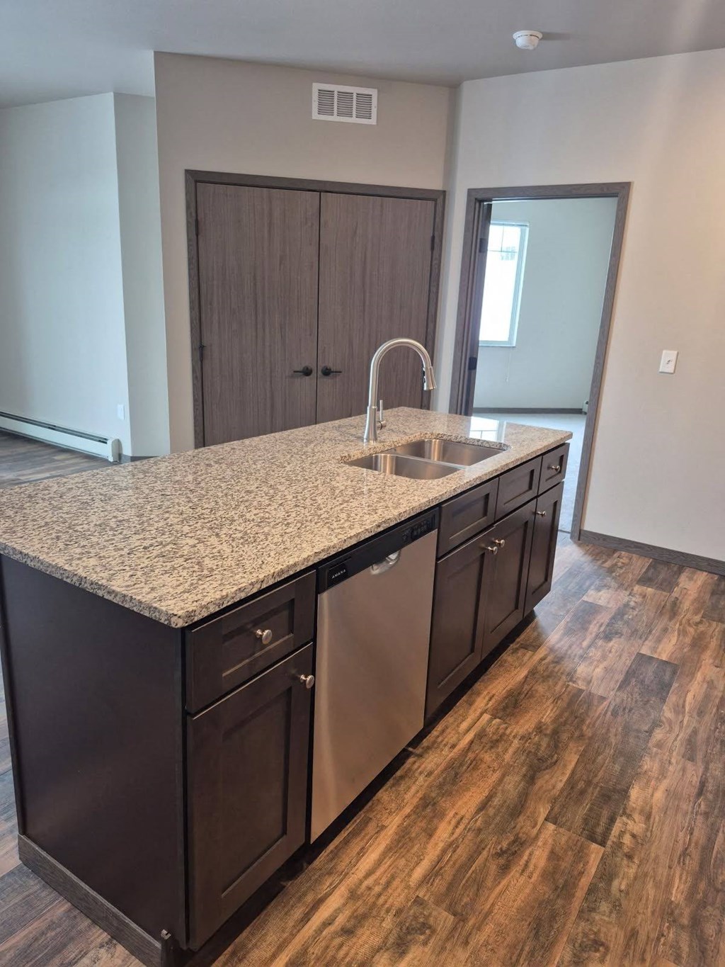 A kitchen with a granite countertop and dark wood cabinets.