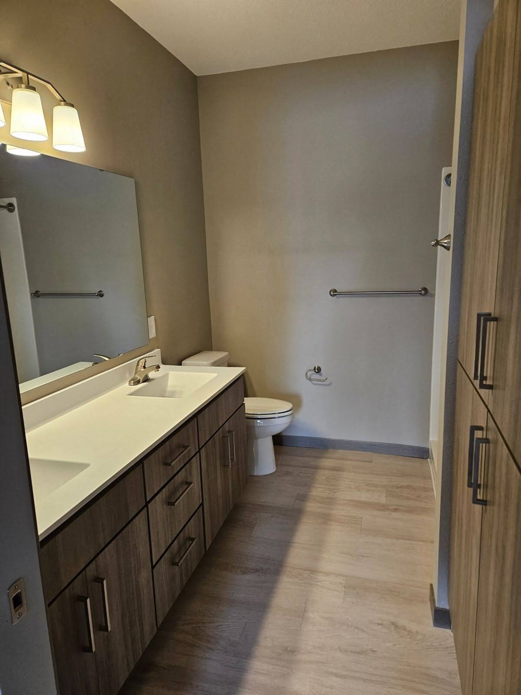 A bathroom with a toilet, sink, and mirror.