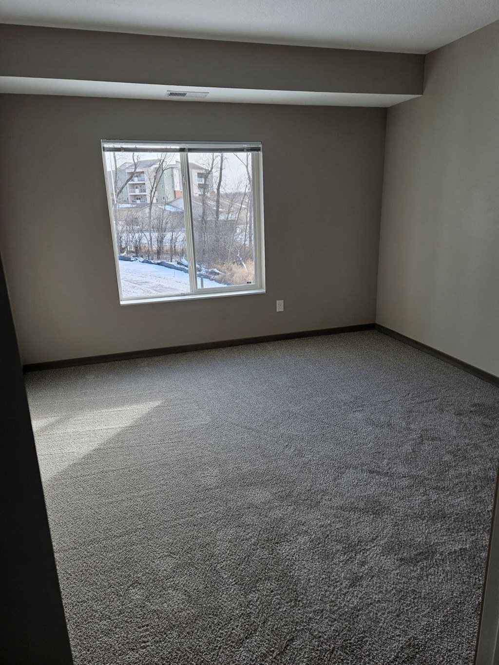 A room with a carpeted floor and a window showing a snowy scene outside.