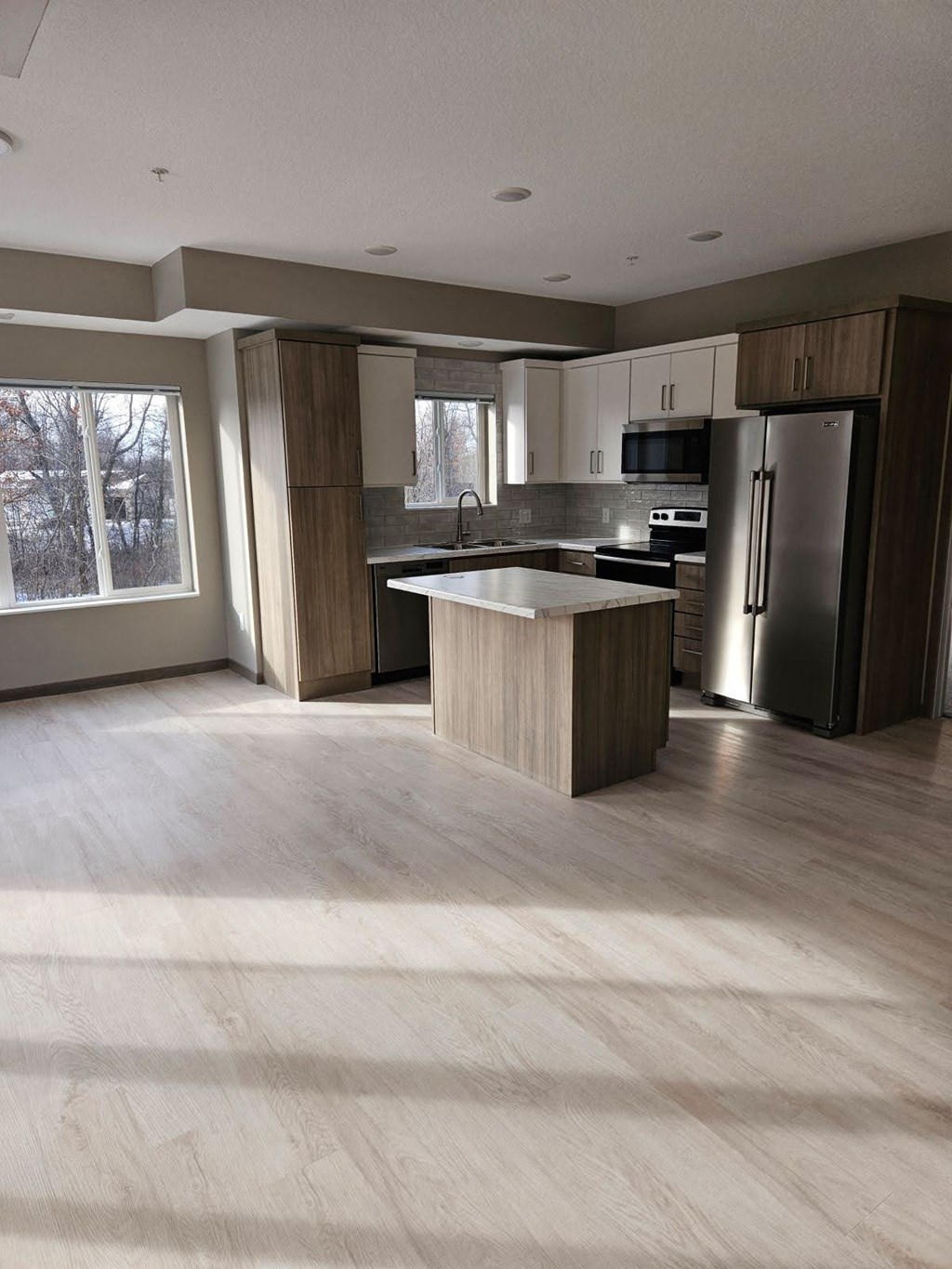 A modern kitchen with a refrigerator, sink, and cabinets.
