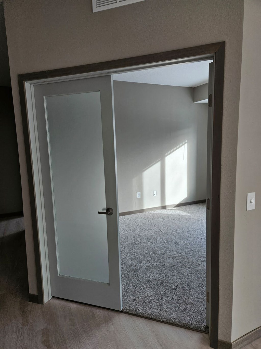 A white door is open to a room with a carpet.
