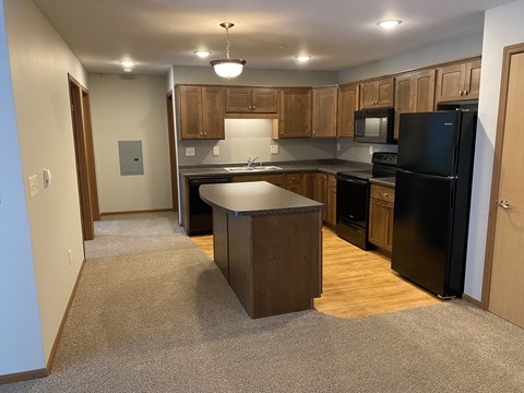 A kitchen with a black fridge and wooden cabinets.