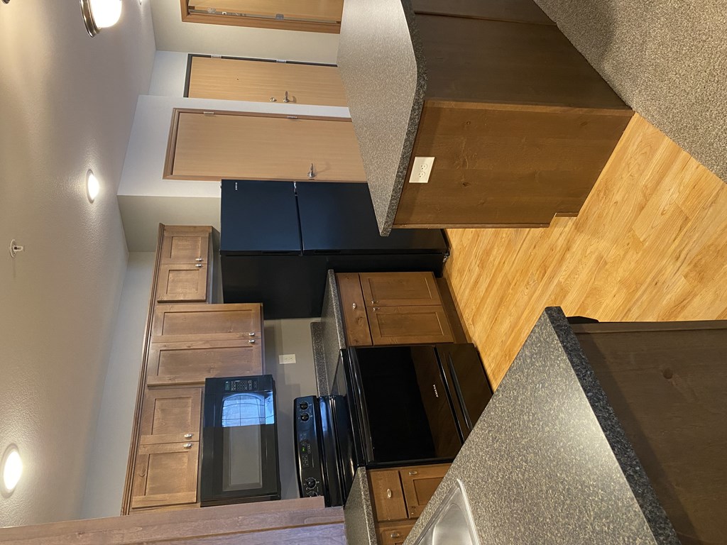 A kitchen with wooden cabinets and black appliances.
