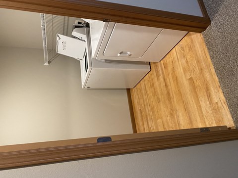 A white air conditioner unit is installed on the ceiling of a room with wooden paneling.