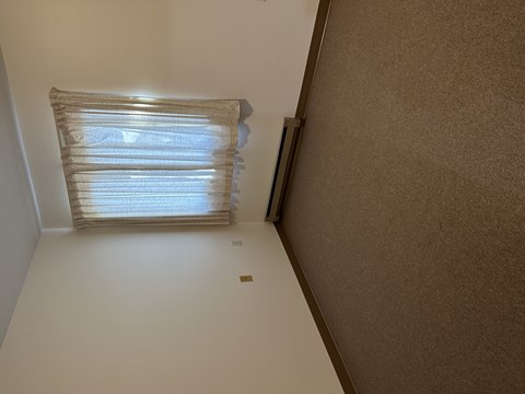 A window with blinds is in the corner of a room.