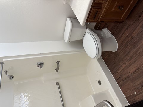 A white toilet with a white lid is mounted on a white wall.